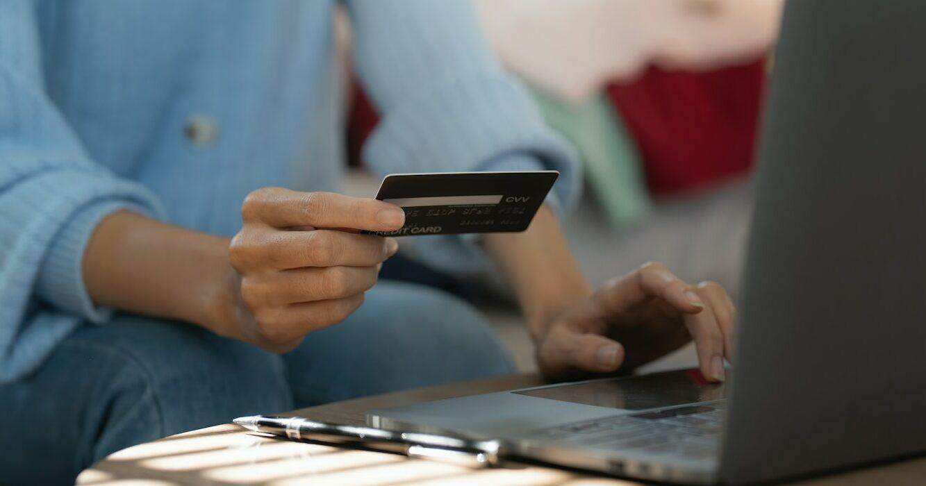 Young person using credit card and laptop computer. Online shopping, e-commerce concept